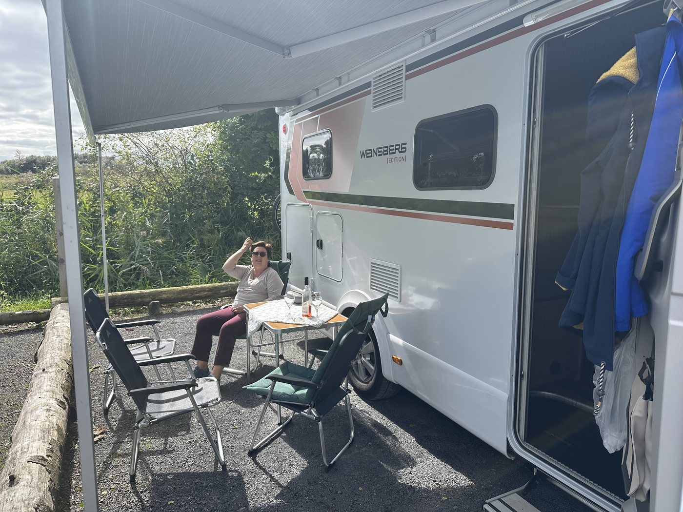 REX Camper Wohnmobil mit ausgefahrener Markise, Tisch und Campingstühlen auf dem Stellplatz in Jork